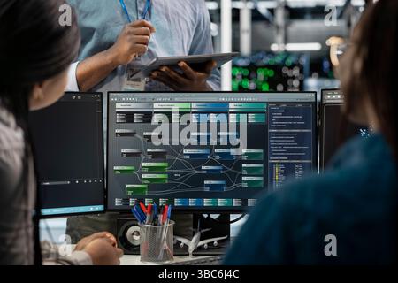 Close up of data center programmers using PC to visualize artificial intelligence neural networks. Server farm IT experts looking at monitor, working together to oversee AI systems Stock Photo