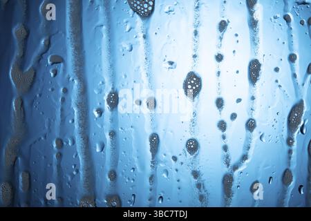 Drops of water with foam on glass on a blue background Stock Photo