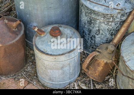 Vintage rusty oil cans of different sizes neglected in a farm workshop Stock Photo