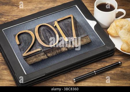 2017 - New Year concept - number in vintage wood type printing blocks on a digital tablet with a cup of coffee Stock Photo