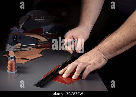The process of making leather goods. The hands of the master craftsman working with a leather product Stock Photo