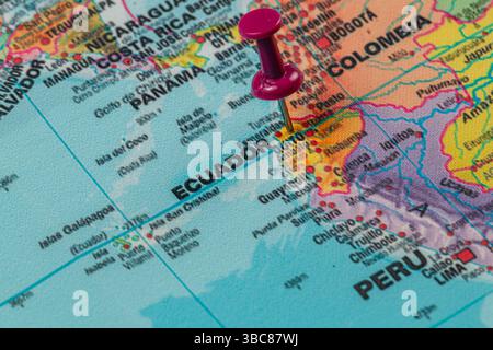 A red pushpin marks Ecuador on a colorful map of South America, showcasing neighboring countries and geographic features in detail, revealing its uniq Stock Photo