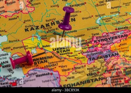A colorful map displays Uzbekistan and surrounding countries, with push pins marking key cities. The region's geography is highlighted for exploration Stock Photo