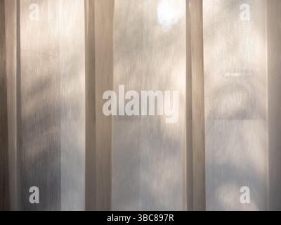 Close-up white transparent curtain on window in the bedroom with warm sunlight. Horizontal window with closed white fabric curtain. Relaxation backgro Stock Photo