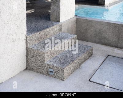 Exposed aggregate finish pool decks with steps with splashing water with no people. Abstract pool texture pattern, light blue background with grid til Stock Photo