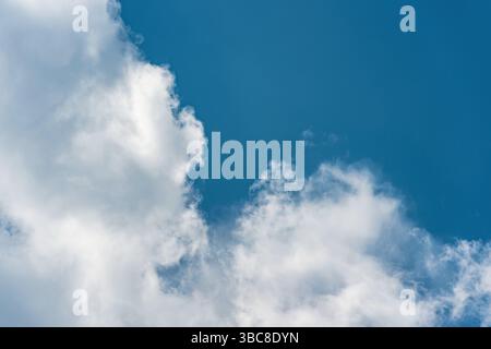 Fluffy white clouds in a bright blue daytime sky Stock Photo