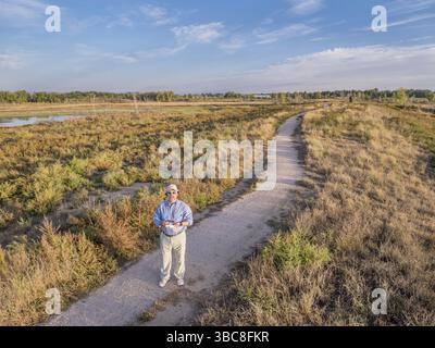 A senior male with a remote controller is flying a drone - a selfportrait shot from a low flying quadcopter drone Stock Photo