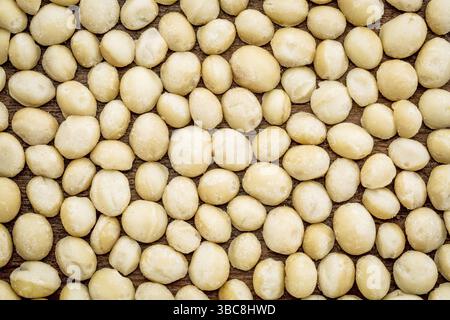 Background texture of shelled macadamia nuts on rustic grunge wood - top view Stock Photo