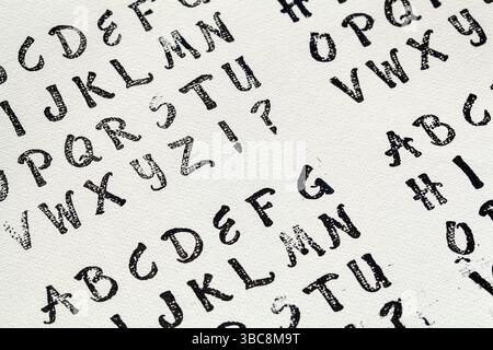 Rubber stamp alphabet abstract printed in black ink on white artist canvas Stock Photo