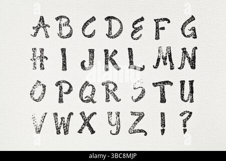 Rubber stamp alphabet printed in black ink on white artist canvas Stock Photo