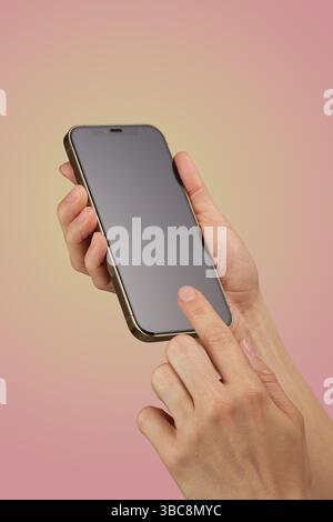 female hand holding and clicking , typing on smartphone display isolated on pink background, mockup , woman using smart phone Stock Photo