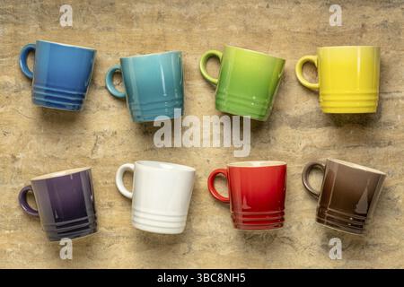 Collection of colorful stoneware coffee cups against textured handmade bark paper Stock Photo