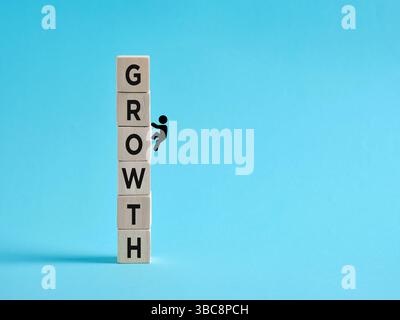 Businessman climbing wooden blocks with growth inscription symbolizing personal and professional development, progress and success Stock Photo