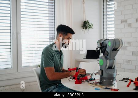 Side view of engineer building and programming a robotic arm at home. Stock Photo