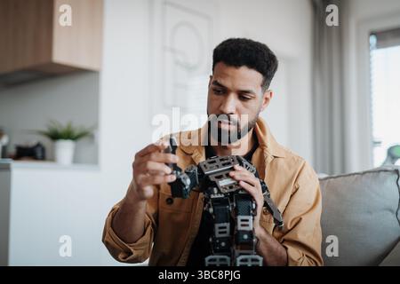 Handsome engineer student working on robot project at home. Stock Photo