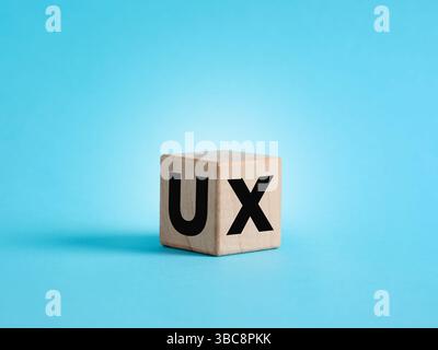 Wooden cube showing the acronym UX, user experience, on blue background, user interface design concept Stock Photo