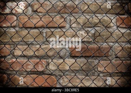 Metal mesh chain-link on the background of an old brick wall Stock Photo