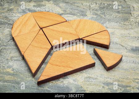 Heart version of tangram, a traditional Chinese Puzzle Game made of different wood parts to build abstract figures from them, on a slate rock backgrou Stock Photo