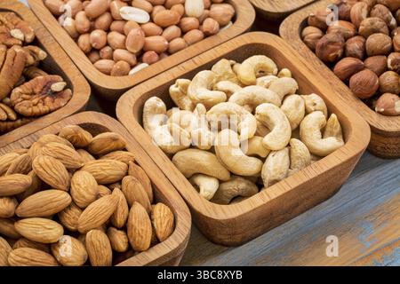 Nuts abstract - cashew, pecan, hazelnut, Spanish peanut in wooden bowls Stock Photo