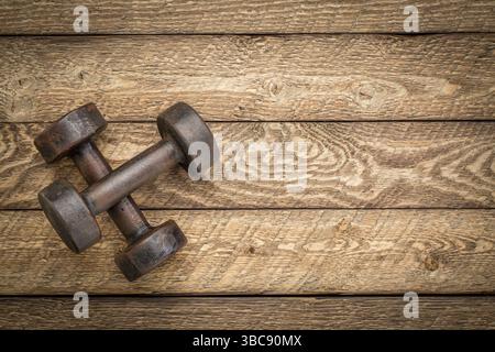 A pair of vintage iron rusty dumbbells on a grained barn wood background with a copy space Stock Photo