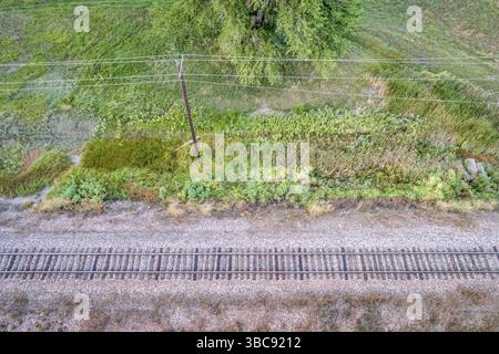 Aerial view of single railroad tracks and electric wires in back ...