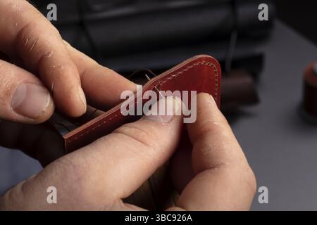 Production of leather wallets. The master's hands sew a leather product Stock Photo
