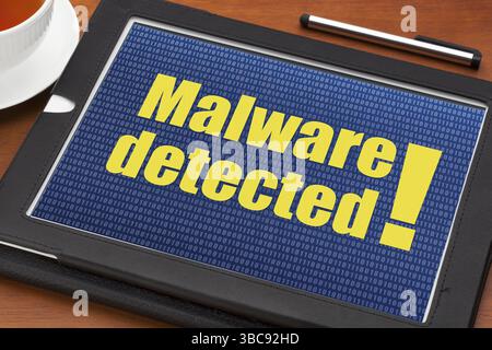 Malware detected alert on a digital tablet with a cup of tea Stock Photo