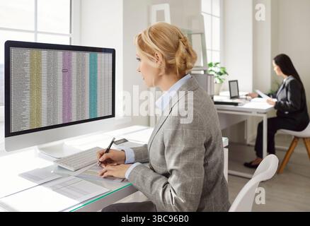 Business accountant working in office concentrated in screen on PC computer using spreadsheet filles Stock Photo