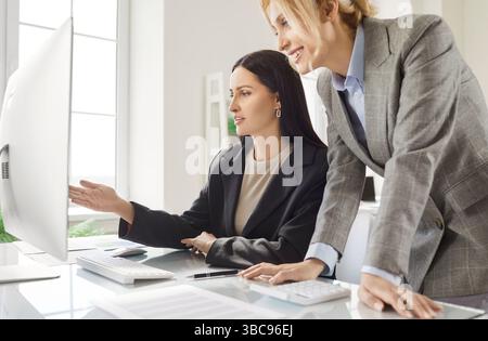 Women Colleagues Using Computer In Office Meeting Stock Photo