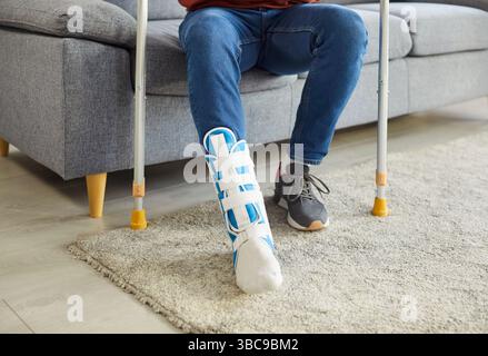 Cropped image of man wearing cast on leg, trying to walk with crutches in house Stock Photo