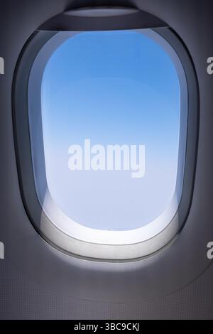 View outside the Airplane window. Looking through a big jet passenger plane window, above the clouds. Nobody, copy space for text, travel photo Stock Photo