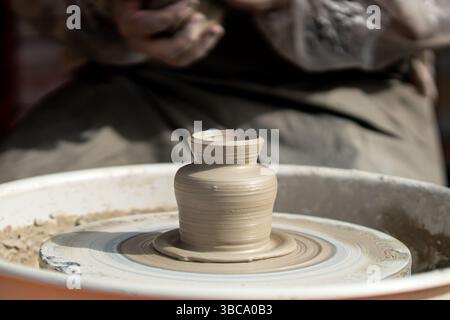 Hands of male potter, ceramist making of an earthenware pot. Potter to make a pitcher on a pottery wheel. Stock Photo
