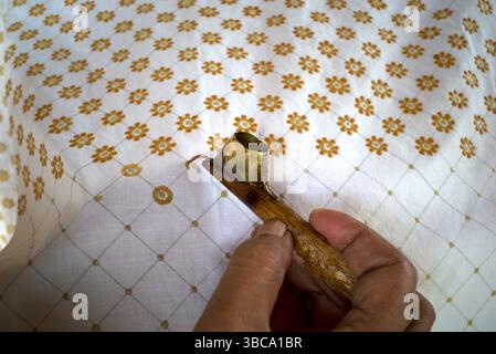 The process of making written batik, a traditional Indonesian clothing, uses canting to make lines and the dots on the fabric. Stock Photo