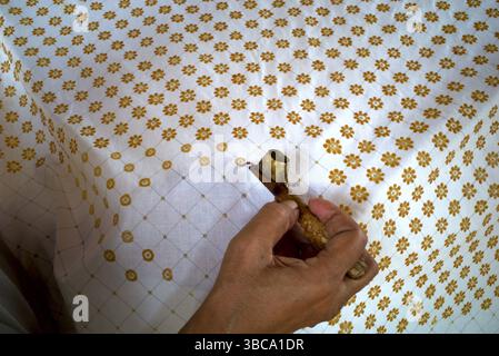 The process of making written batik, a traditional Indonesian clothing, uses canting to make lines and the dots on the fabric. Stock Photo