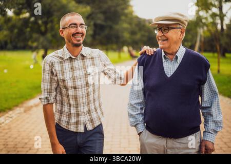 Portrait of happy grandfather and grandson in park. They are walking and having fun. Stock Photo