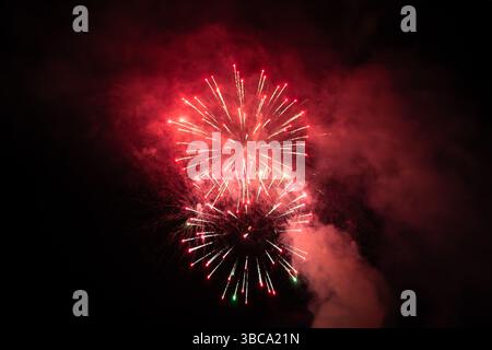 christmas celebration fireworks. red fireworks on the black night sky. festive new year background Stock Photo
