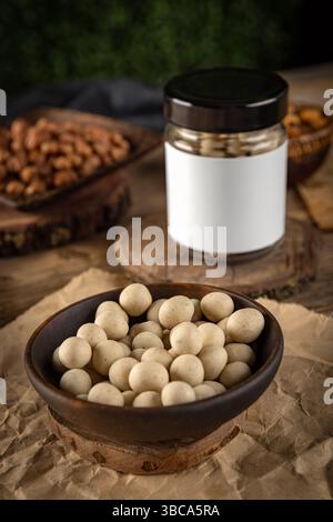 Bowl of white chocolate covered peanuts with blank label jar in background Stock Photo