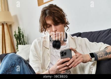 Young man engaged in his studies at home, using his phone and listening through headphones. Stock Photo