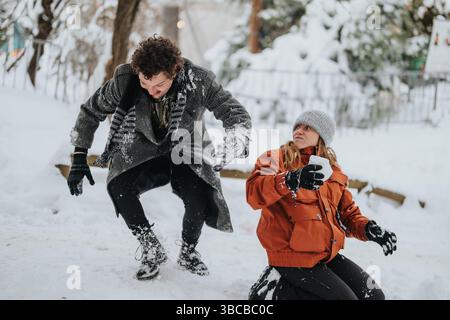 Friends enjoying a playful snow fight in a winter landscape Stock Photo
