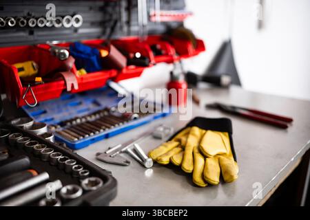 Yellow Protective Gloves On A Mechanic Workbench With Instruments And Tools Stock Photo