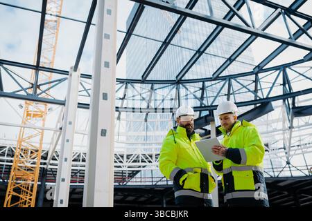 Construction managers using digital tablet on site, reviewing project plans. Stock Photo