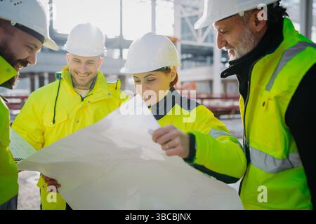 Team of engineers and construction workers inspecting building progress. Stock Photo