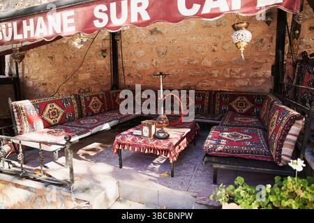 Cozy traditional Turkish cafe 'Gülhane Sur Cafe' in Istanbul. Outdoor seating with colorful carpets, hookah, and mosaic lamps by a stone wall Stock Photo