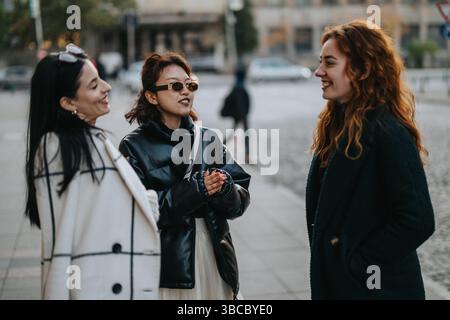 Three individuals engaging in a cheerful conversation outdoors during the day Stock Photo
