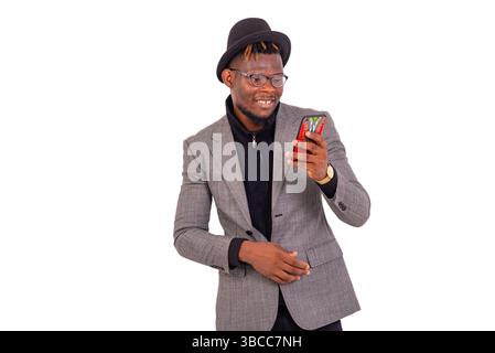 handsome young business man wearing elegant suit using mobile phone while smiling. Stock Photo