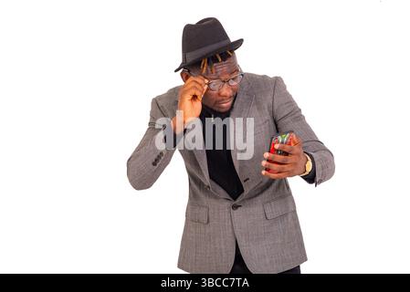 handsome young business man wearing elegant suit wearing his glasses looking at mobile phone screen. Stock Photo