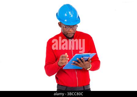 an engineer man wearing hard hat standing against white background looking at a notepad. Stock Photo