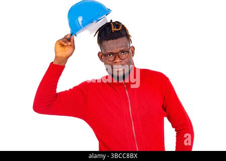 .a young man with glasses standing on white background taking off safety helmet and looking at the camera smiling. Stock Photo