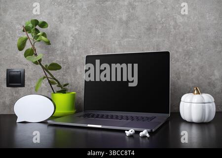 Laptop with blank screen, office supplies and potted ficus. Stock Photo