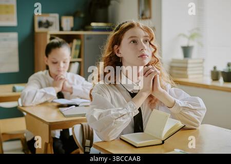 Students engaged in studying within classroom environment featuring books, notebooks, and desks. Bright lighting highlights studious atmosphere among Stock Photo